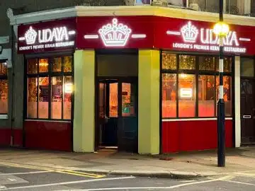 Street‑level view of Udaya Kerala Restaurant on Katherine Road in East Ham, London, with its white frontage, large bay windows and the green‑and‑red sign that reads “UDAYA – Indian & Kerala Cuisine
