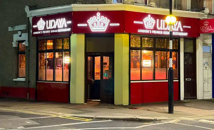 Street‑level view of Udaya Kerala Restaurant on Katherine Road in East Ham, London, with its white frontage, large bay windows and the green‑and‑red sign that reads “UDAYA – Indian & Kerala Cuisine